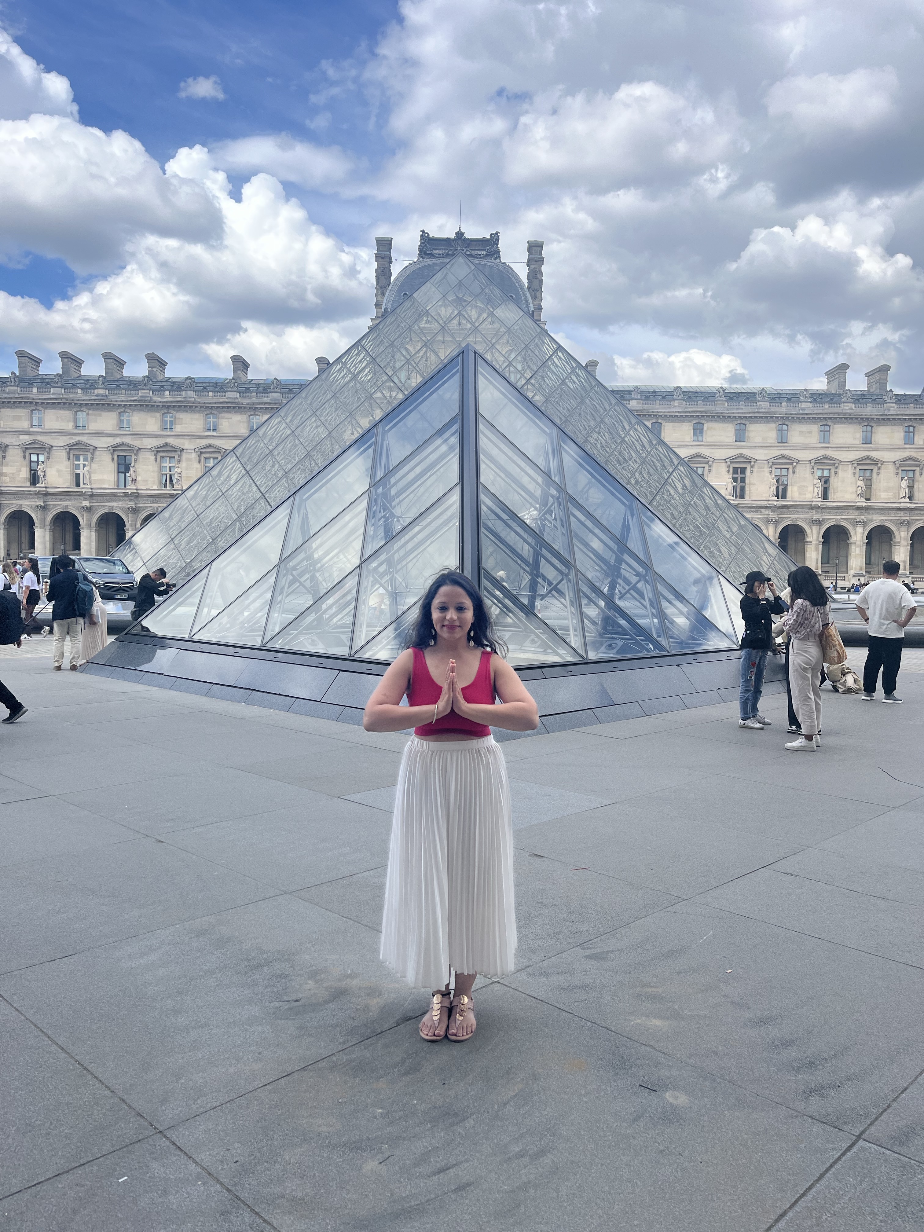 Yashna in namaste in front of the Louvre pyramid