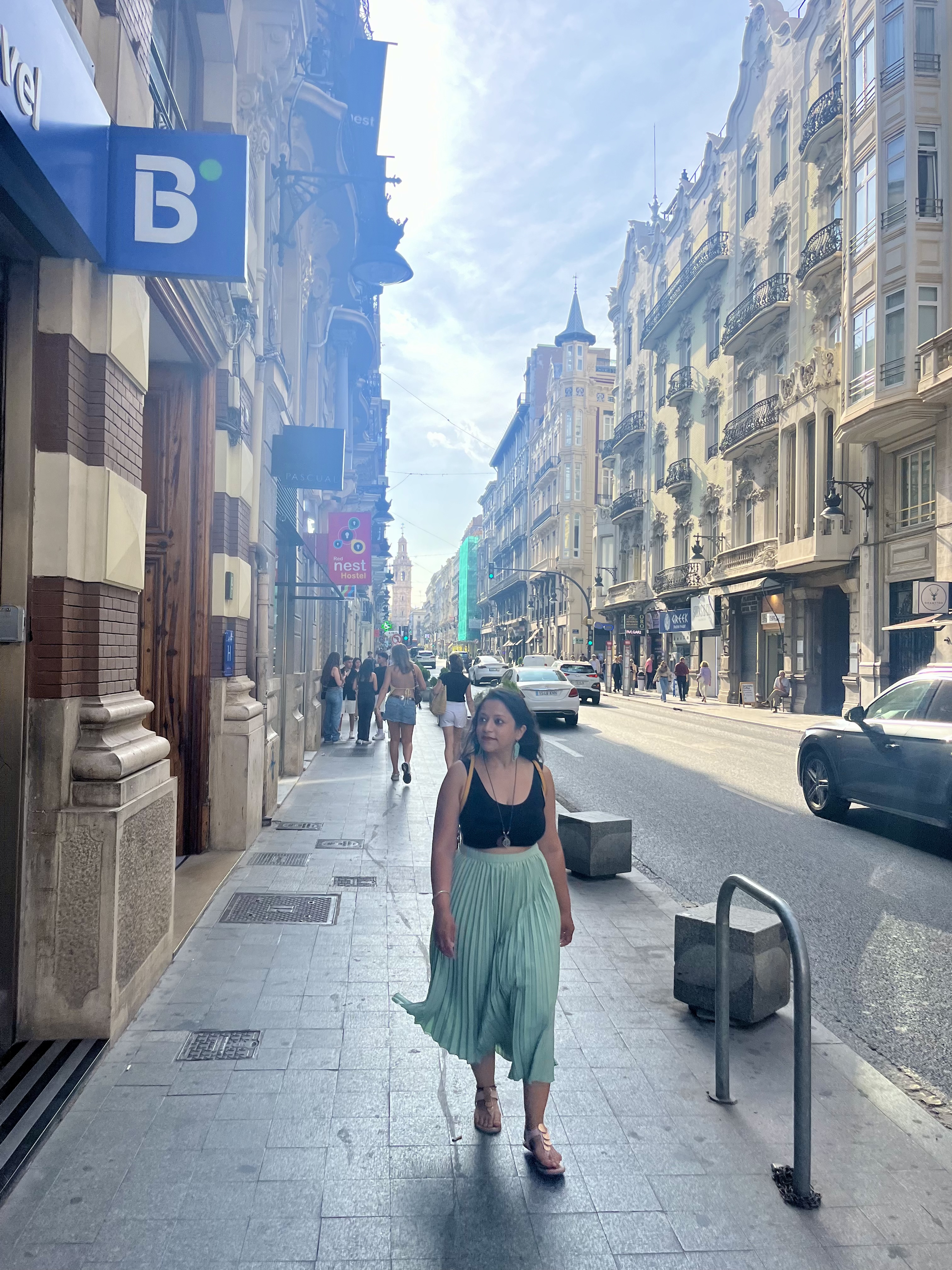 Yashna walking along a sunlit city street