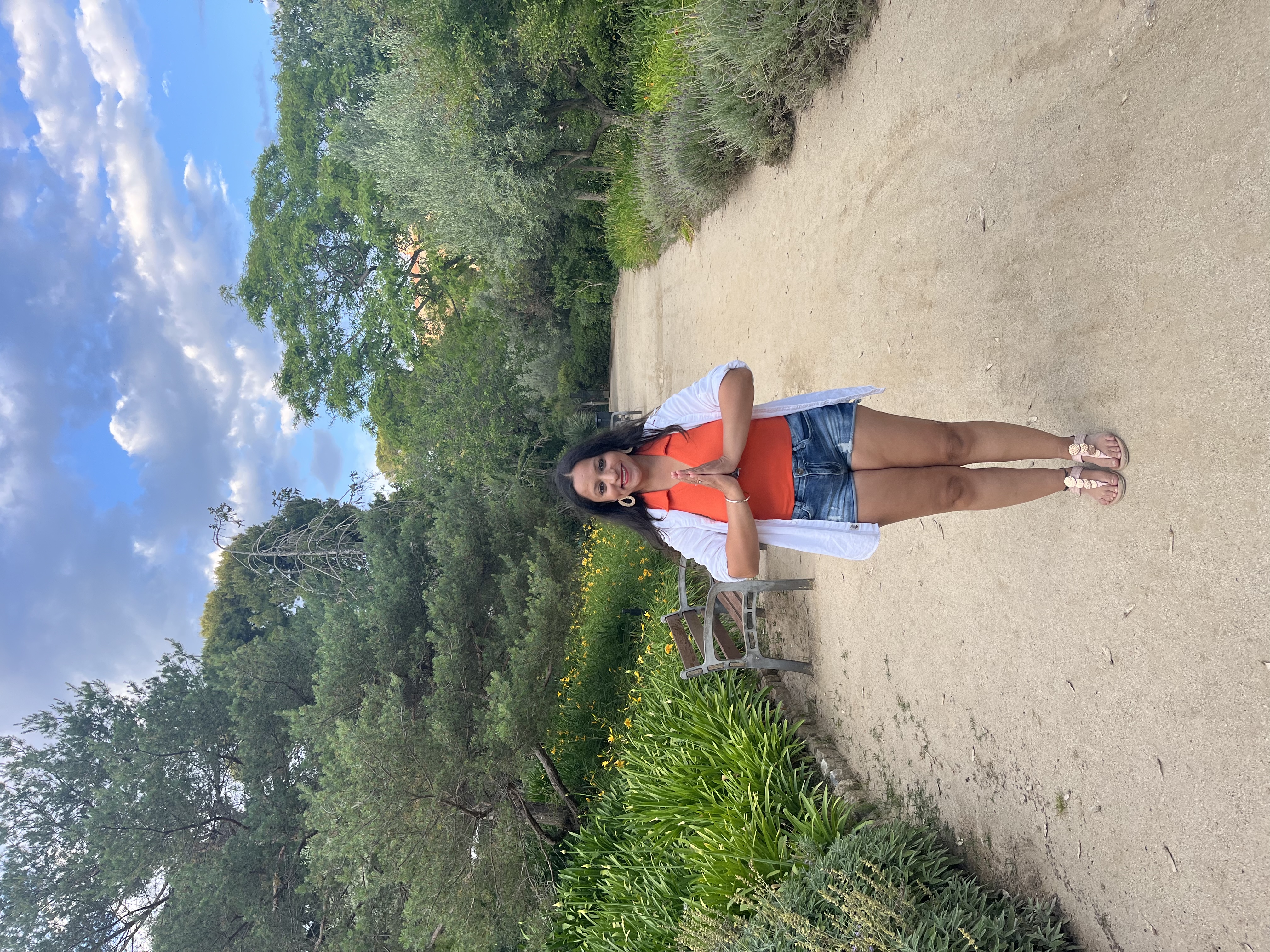 Yashna in namaste on a sandy garden path